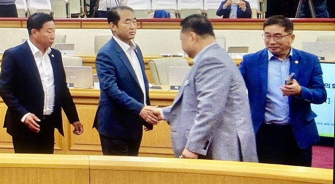 김경일 시장이 지난 14일 파주시의회 본회의장에서 예산 삭감에 격분 돌출행동을 한 후 민주당 최유각 의원과 악수를 나누고 있다. 최 의원의 표정이 당시 상황을 설명해주고 있다. 사진 파주바른신문 영상 캡쳐