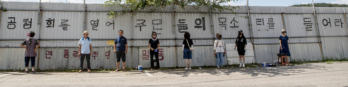 파주읍 연풍리 주민들이 22일 대추벌 성매매집결지 담벼락에 파주시의 일방적 개발에 항의하는 뜻으로 '주민 공청회를 열어 주민들의 목소리를 들어라!'라는 문구를 썼다. 사진 조영애 기자