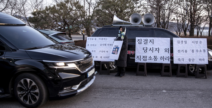 대추벌생존권대책위 회원인 성노동자가 1월 30일 이동시장실이 열리고 있는 파주읍사무소 앞에서 김경일 시장의 황제수영을 비판하는 피켓을 목에 걸고 1인 시위를 하고 있다(위). 이동시장실을 마친 김경일 시장이 관용차를 타고 1인시위 현장을 지나고 있다. 사진 조영애 기자